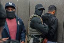 FILE - Immigration and Customs Enforcement agents escort a detained immigrant into an elevator ...