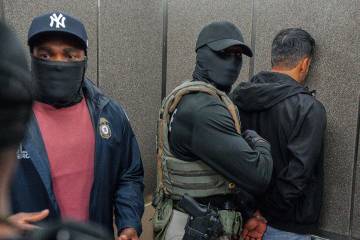 FILE - Immigration and Customs Enforcement agents escort a detained immigrant into an elevator ...