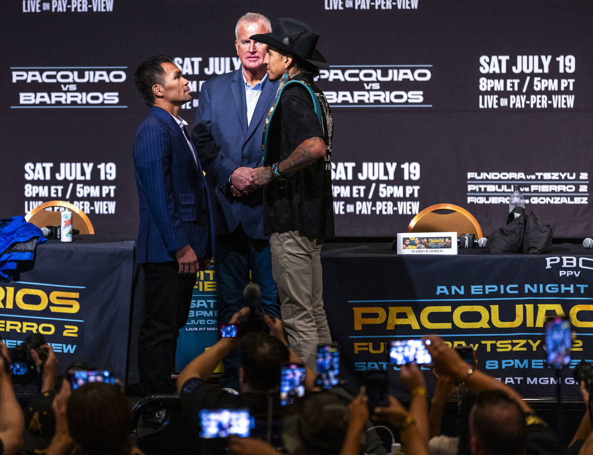 Manny Pacquiao and Mario Barrios face off for the crowd with promoter Tom Brown in between duri ...