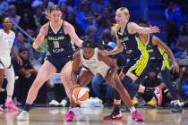 Las Vegas Aces guard Jackie Young (0) drives against Dallas Wings guard Paige Bueckers (5) and ...