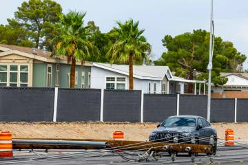 A Mercedes is stuck between downed power lines as crews continue on storm damage repair along S ...