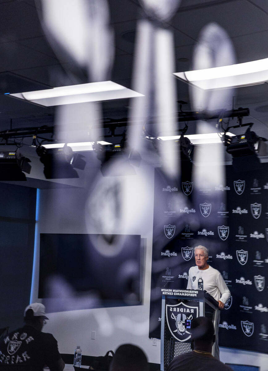 Raiders head coach Pete Carroll is reflected in a Super Bowl trophy image hanging in the room a ...