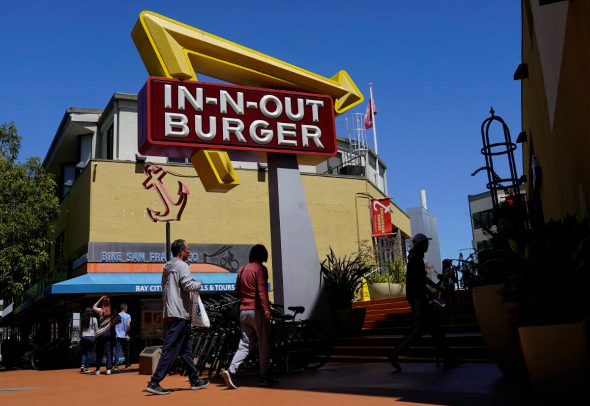 People walk below an In-N-Out Burger restaurant sign in San Francisco, Aug. 25, 2022. (AP Photo ...