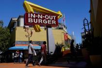 People walk below an In-N-Out Burger restaurant sign in San Francisco, Aug. 25, 2022. (AP Photo ...