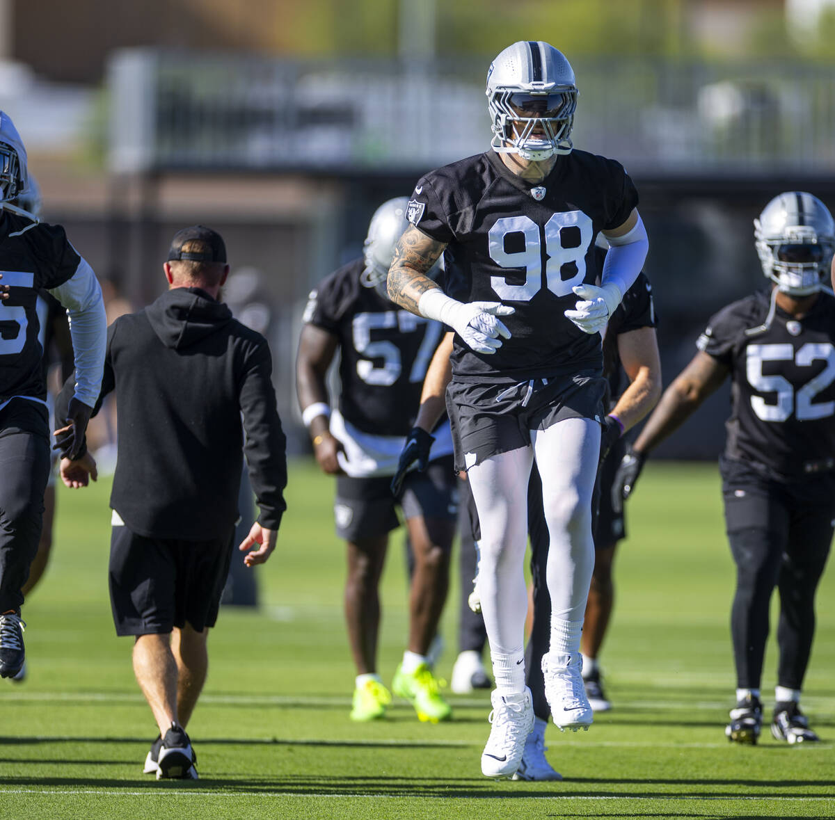 Raiders defensive end Maxx Crosby (98) warms up with teammates during the first day of training ...