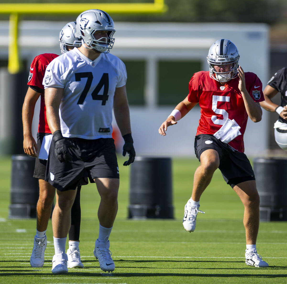 Raiders quarterback Cam Miller (5) warms up with teammates during the first day of training cam ...