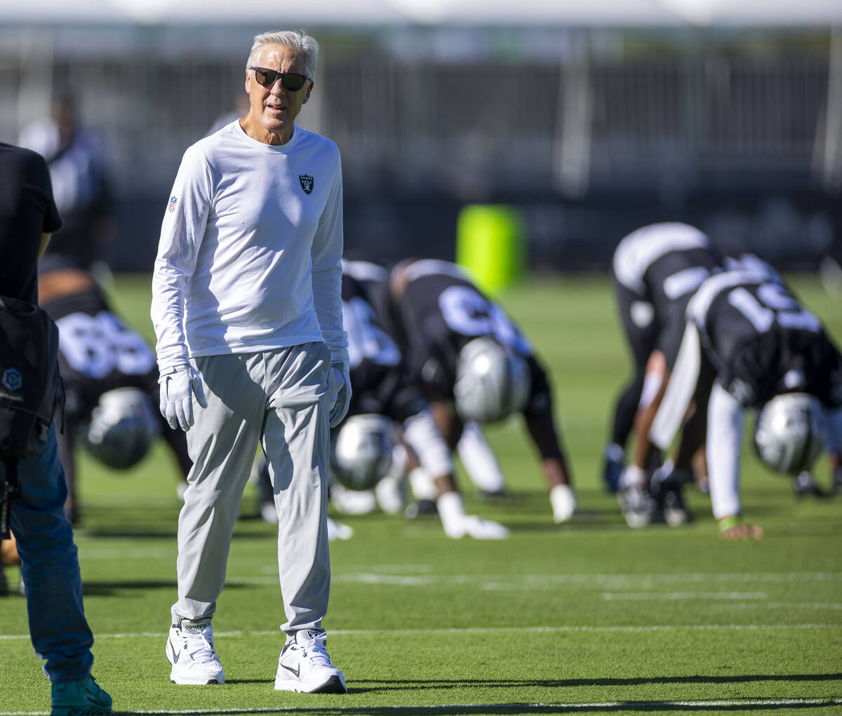 Raiders head coach Pete Carroll keeps an eye on his players as they warm up during the first da ...