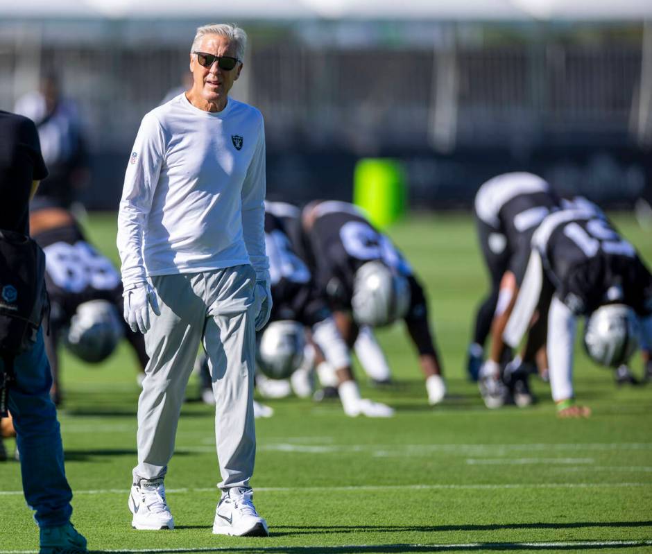 Raiders head coach Pete Carroll keeps an eye on his players as they warm up during the first da ...