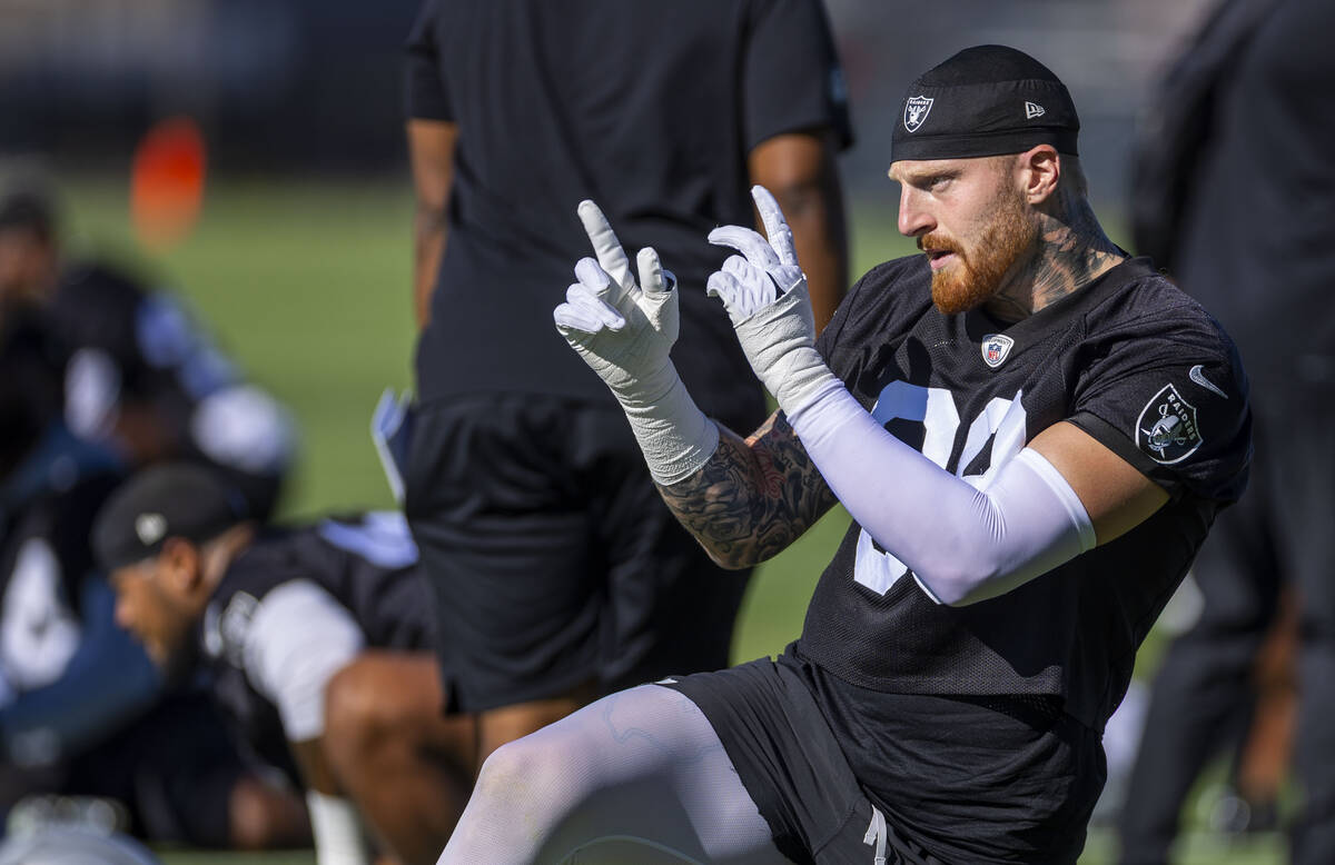 Raiders defensive end Maxx Crosby (98) signals a teammate as he begins to stretch during the fi ...