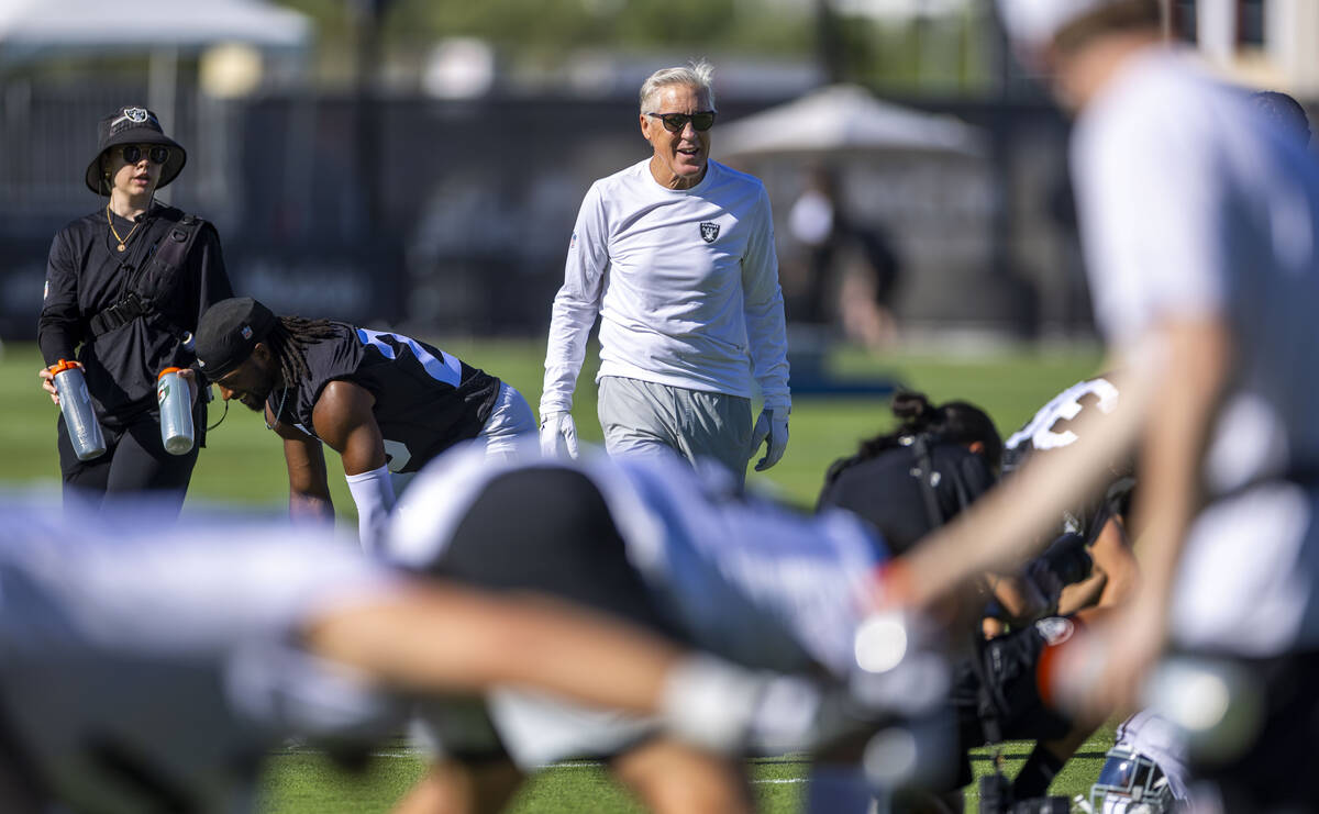 Raiders head coach Pete Carroll keeps an eye on his players as they warm up during the first da ...