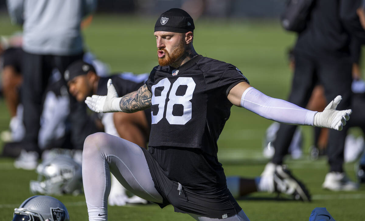 Raiders defensive end Maxx Crosby (98) stretches with teammates during the first day of trainin ...