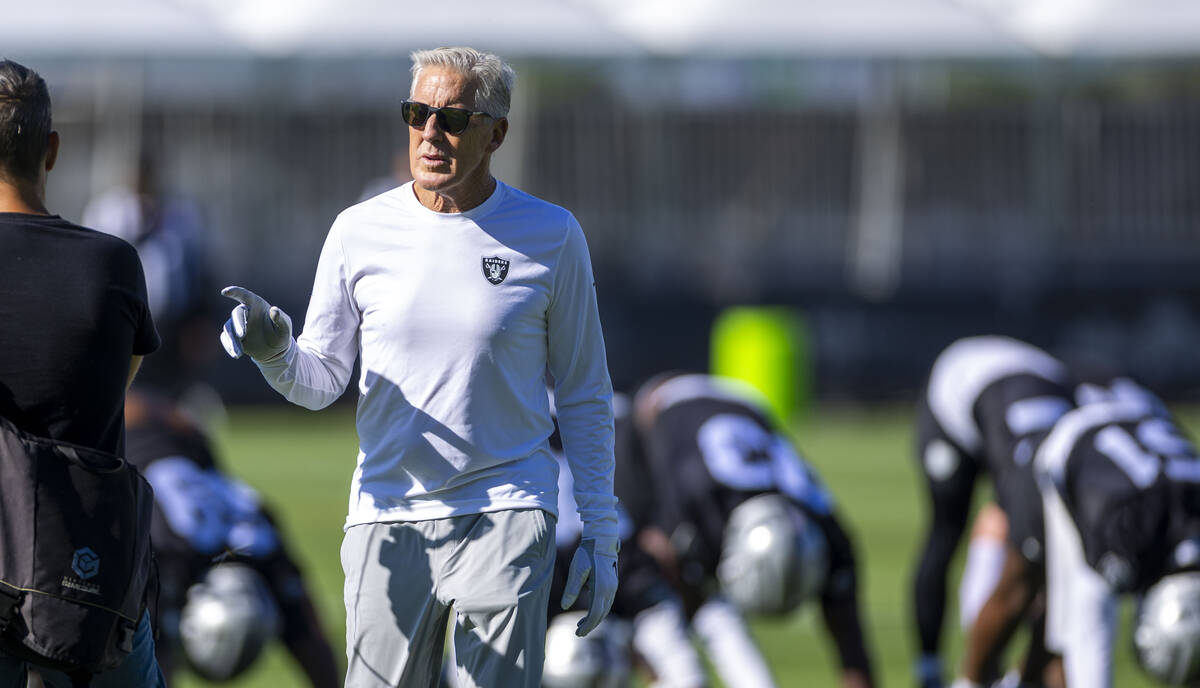 Raiders head coach Pete Carroll talks to a staffer as players warm up during the first day of t ...