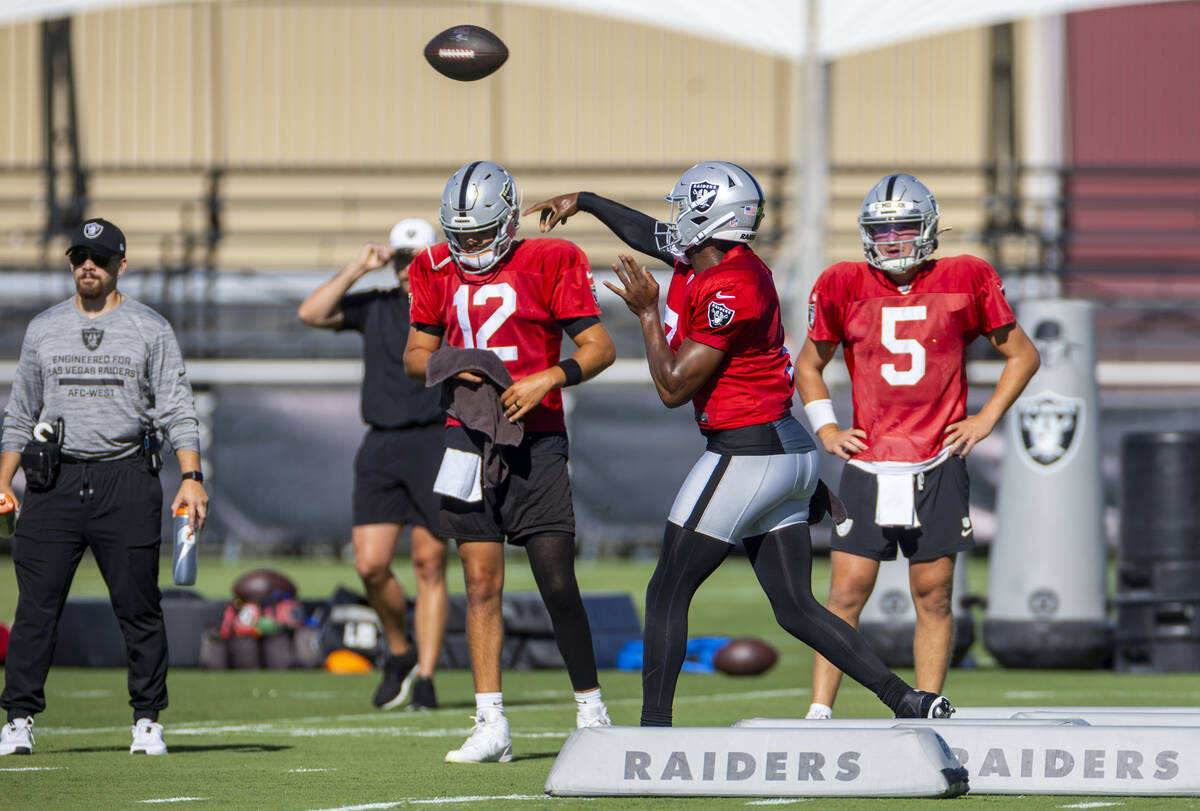 Raiders quarterback Geno Smith (7) gets off a pass between quarterbacks Aidan O'Connell (12) an ...