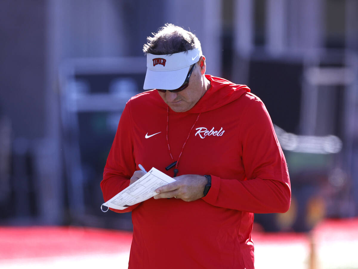 UNLV head coach Dan Mullen takes a note during the first day of football camp at the Fertitta F ...