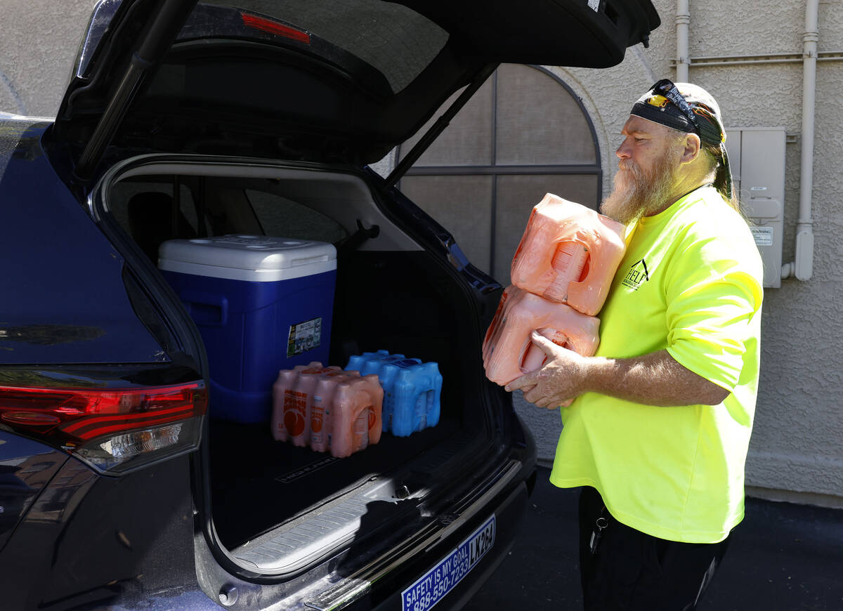 Chris Engle, a HELP of Southern Nevada outreach worker, loads bottled water into an SUV, to be ...