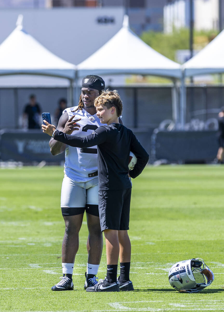 Raiders running back Ashton Jeanty (2) takes a "selfie" with a young fan during an in ...