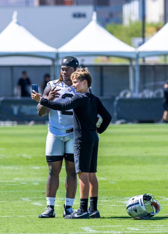 Raiders running back Ashton Jeanty (2) takes a "selfie" with a young fan during an in ...