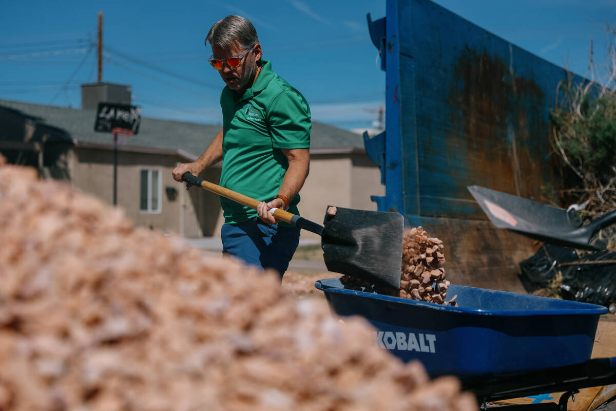 Bob Cleveland, CEO of Rebuilding Together Southern Nevada, shovels rocks into a wheelbarrow whi ...