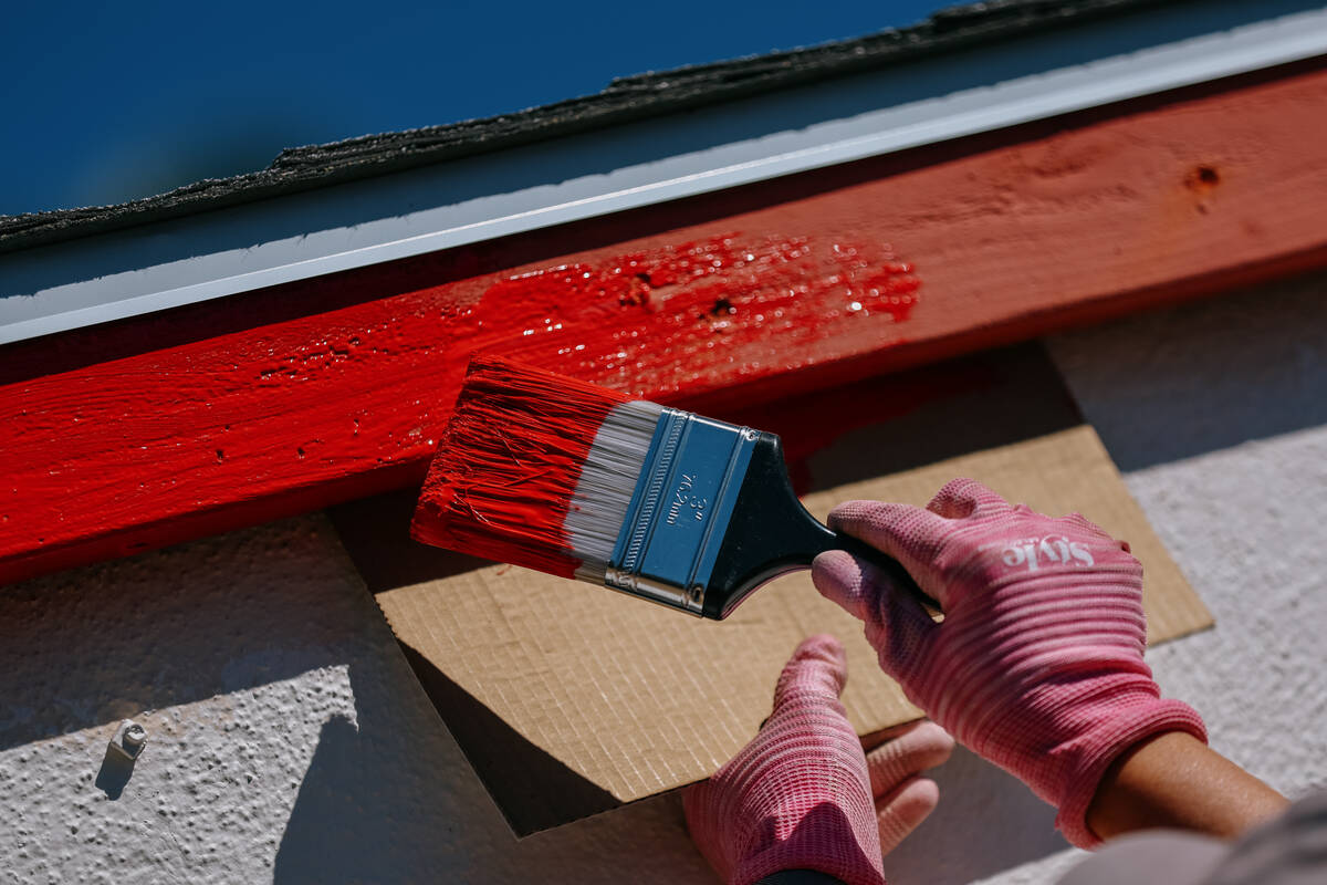 Realtor Peach Freeman paints the trim of a home as she volunteers with Las Vegas Realtors and R ...
