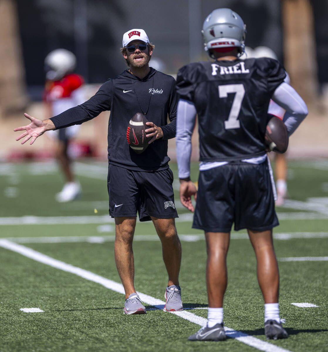 UNLV offensive coordinator and quarterbacks coach Corey Dennis works on technique with quarterb ...