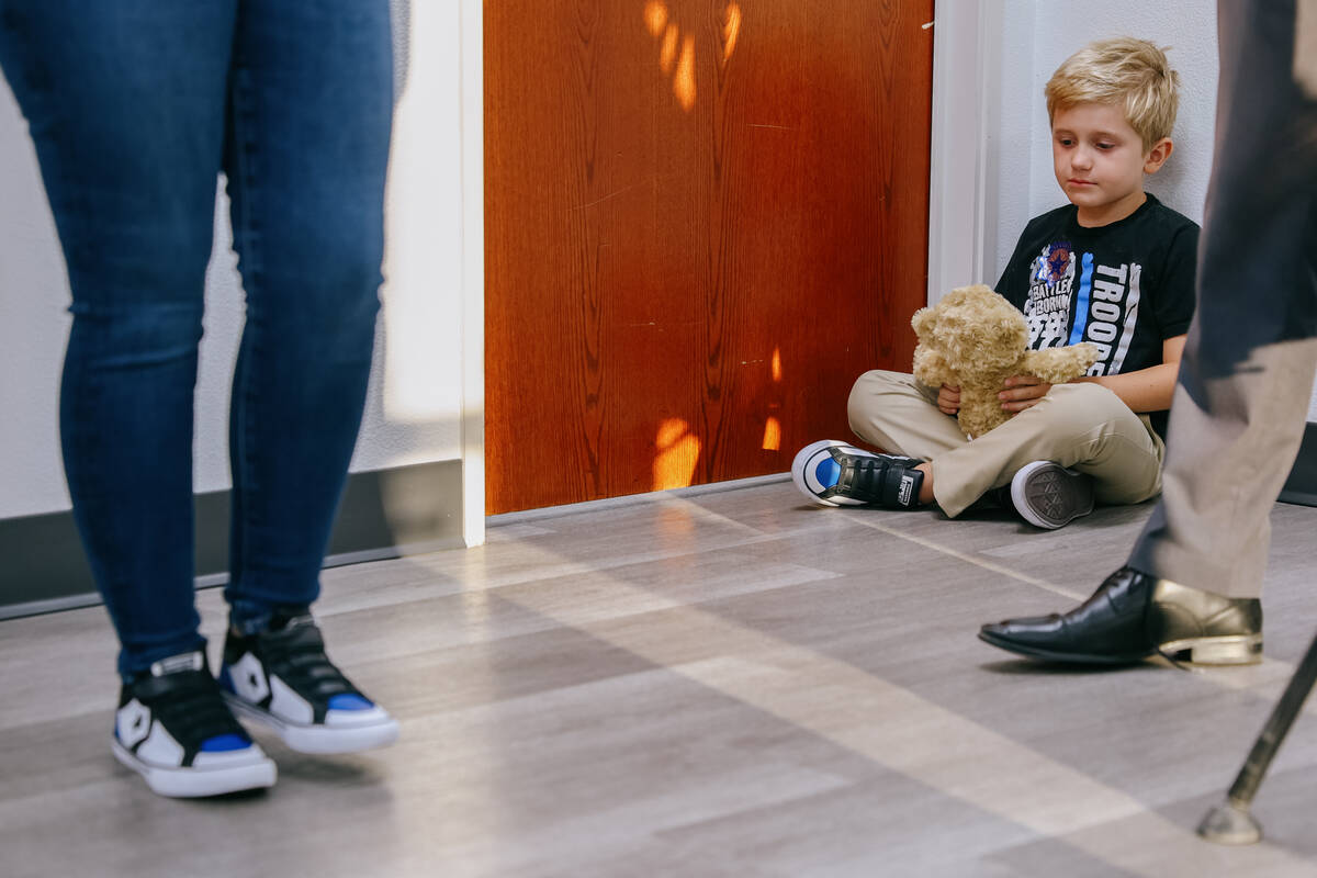 Raylan May, 7, sits with his teddy bear while his mother Joanna speaks about his father, Micah ...