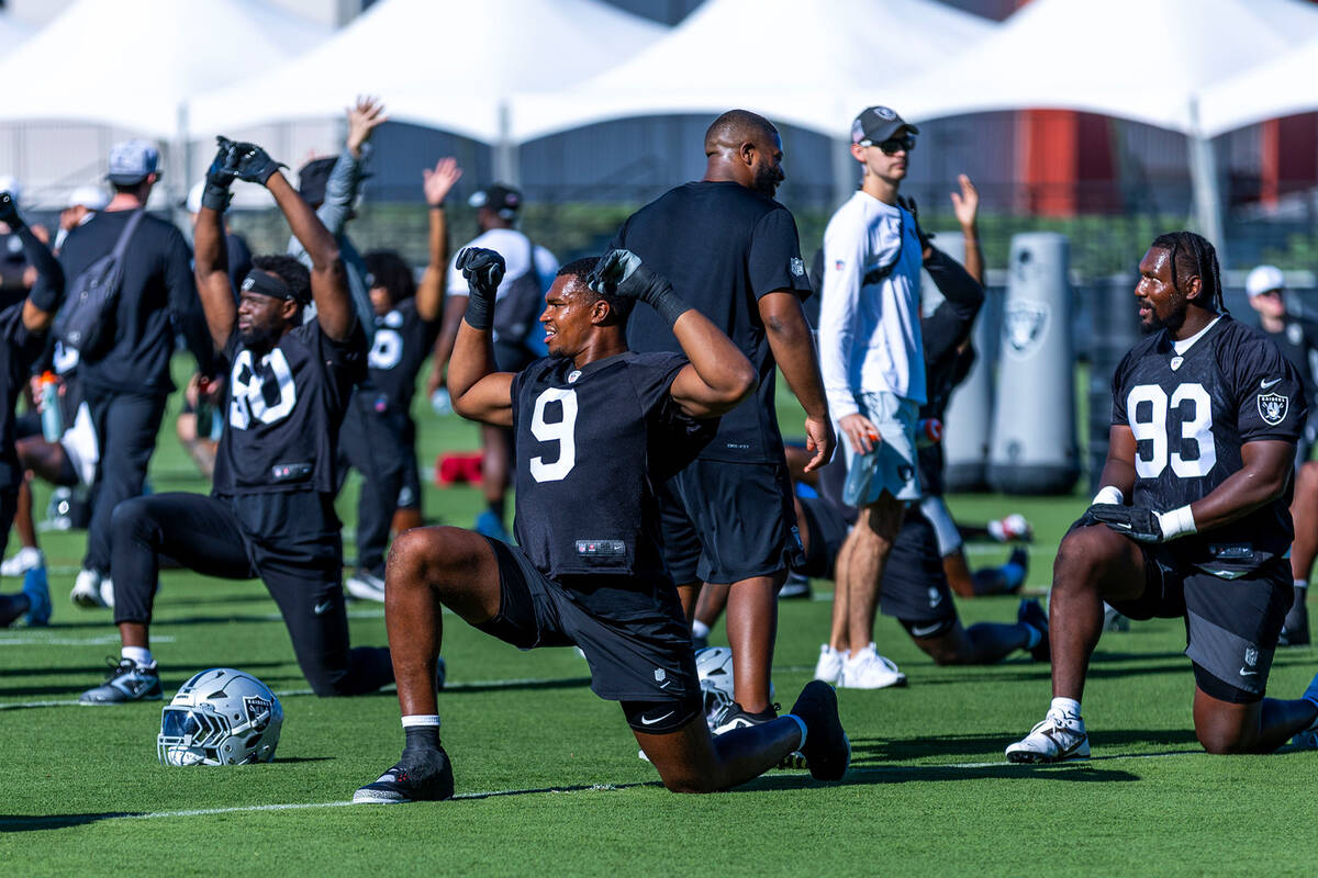 Raiders defensive end Tyree Wilson (9) and defensive tackle Zach Carter (93) stretch with teamm ...