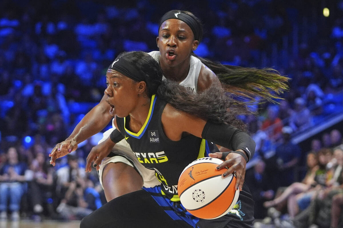 Dallas Wings guard Arike Ogunbowale, front, dribbles against Las Vegas Aces guard Jackie Young, ...