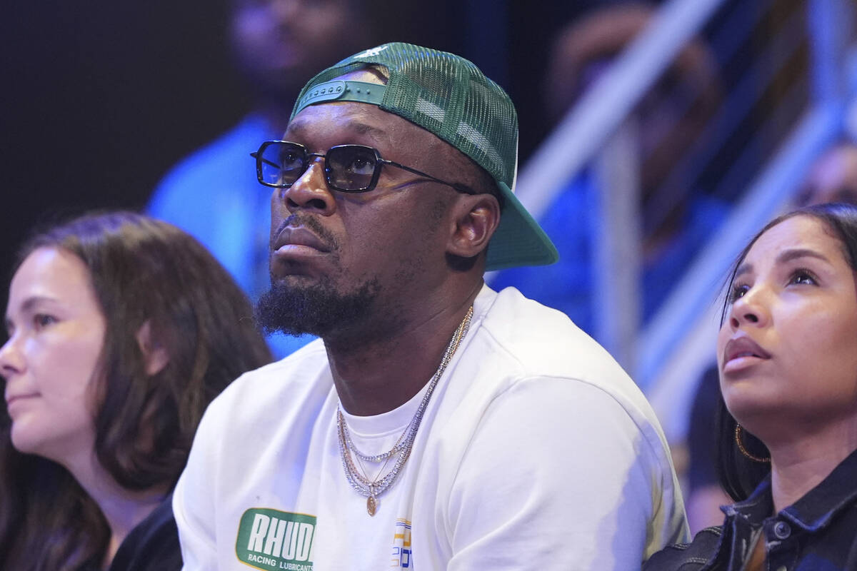 Olympic champion sprinter Usain Bolt, center, watches the second half of a WNBA basketball game ...