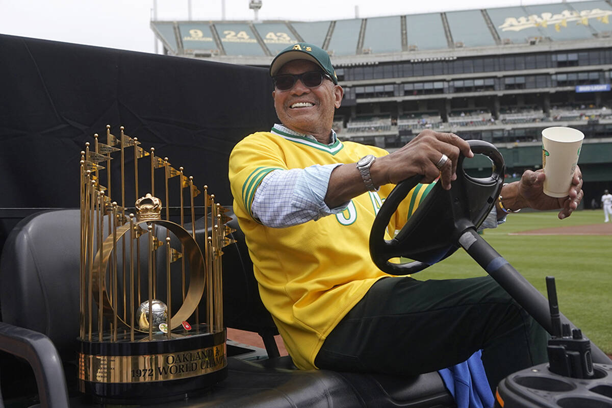 Reggie Jackson smiles while sitting next to the World Series trophy during a celebration of the ...