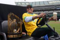 Reggie Jackson smiles while sitting next to the World Series trophy during a celebration of the ...