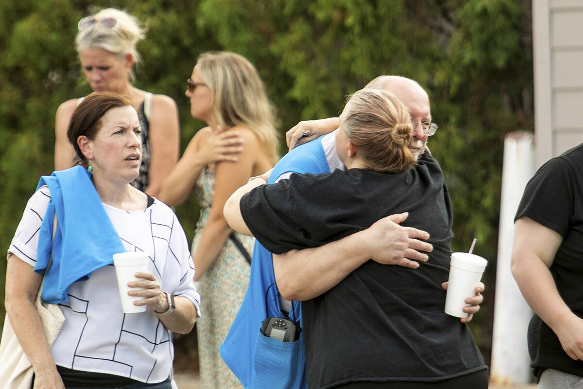 Walmart employees and customers wait outside while law enforcement investigates the scene after ...