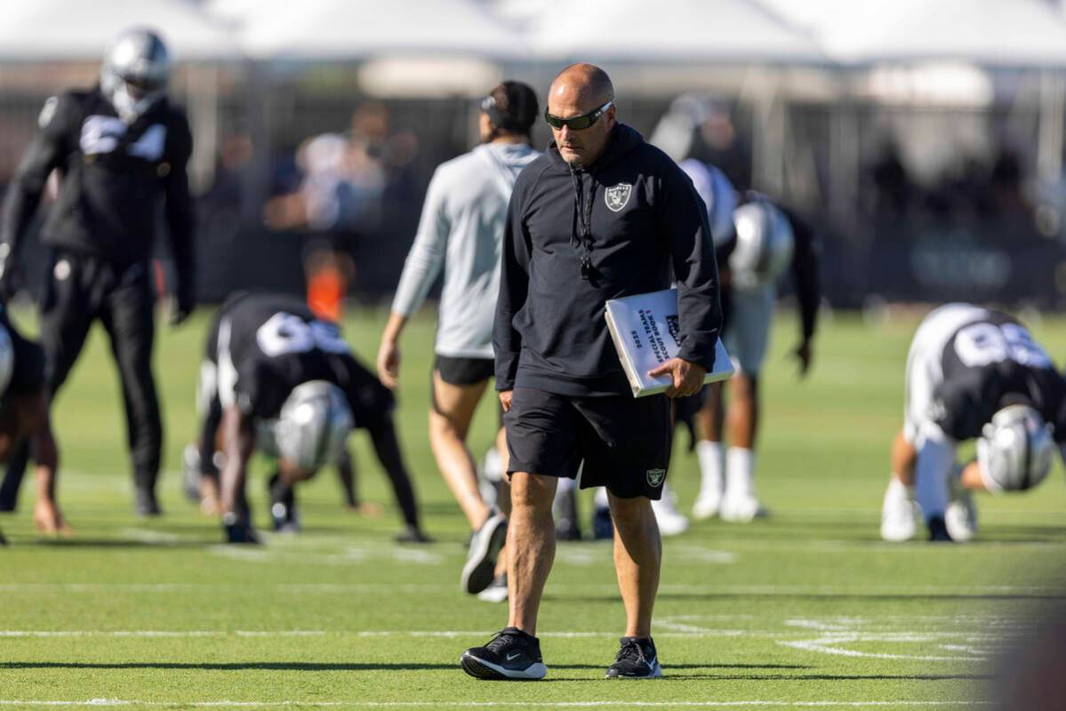 Raiders special teams coordinator Tom McMahon walks the field with his playbook during the team ...