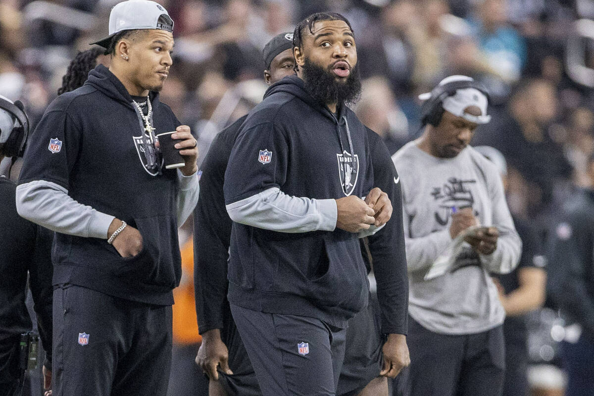 Raiders defensive tackle Christian Wilkins, right, watches the team play from the sideline duri ...