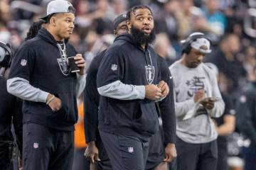 Raiders defensive tackle Christian Wilkins, right, watches the team play from the sideline duri ...