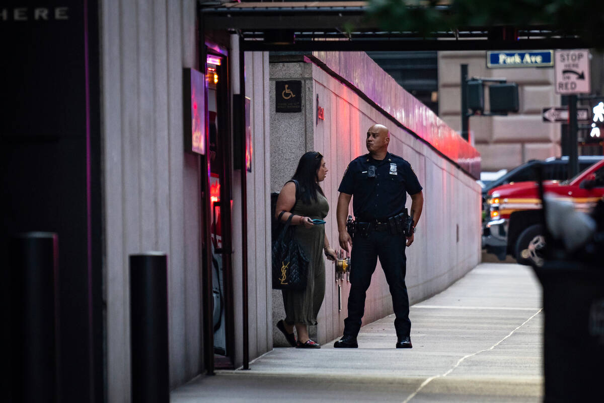 A New York police officer talks with a woman as she exits a Manhattan office building where two ...