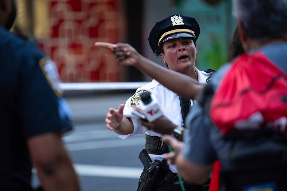 A New York police officer directs bystanders and members of the media outside a Manhattan offic ...