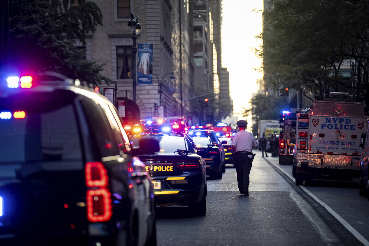 A New York police officer stands watch on 52nd Street outside a Manhattan office building where ...