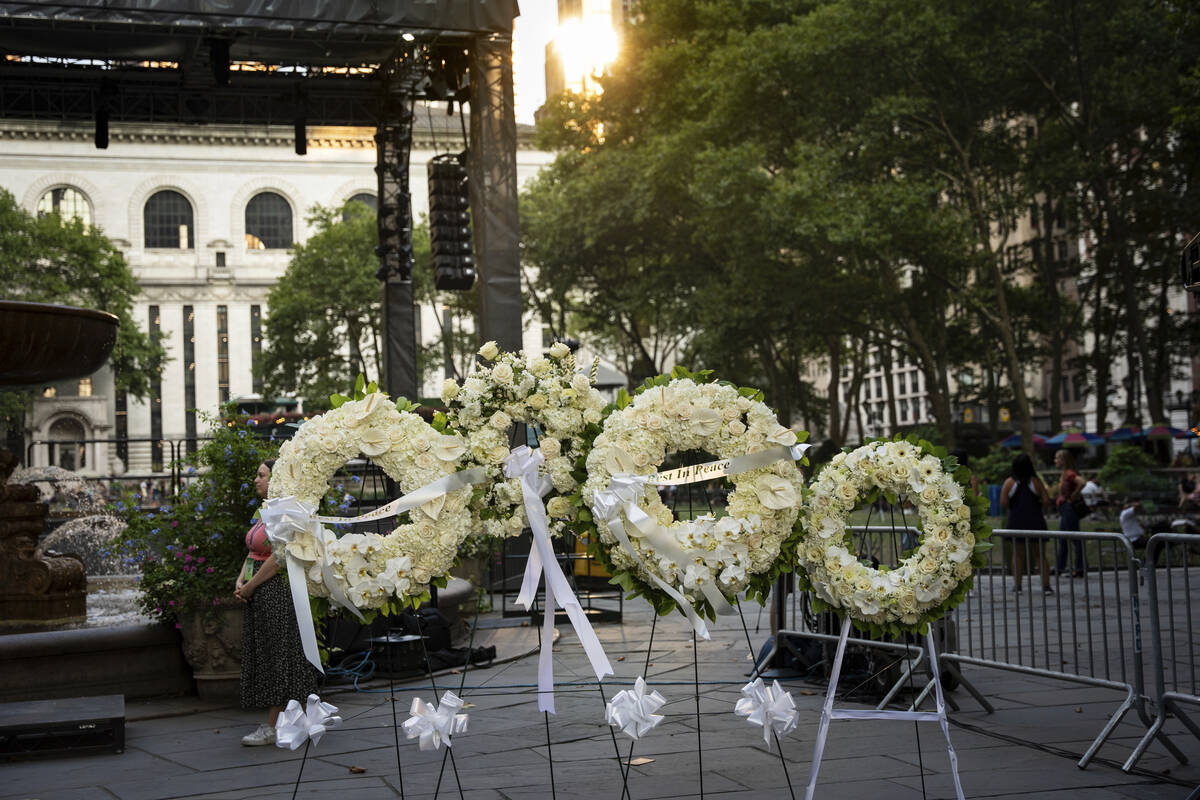 Flower wreaths with the words "Rest In Peace" stand at a vigil for the four people ki ...