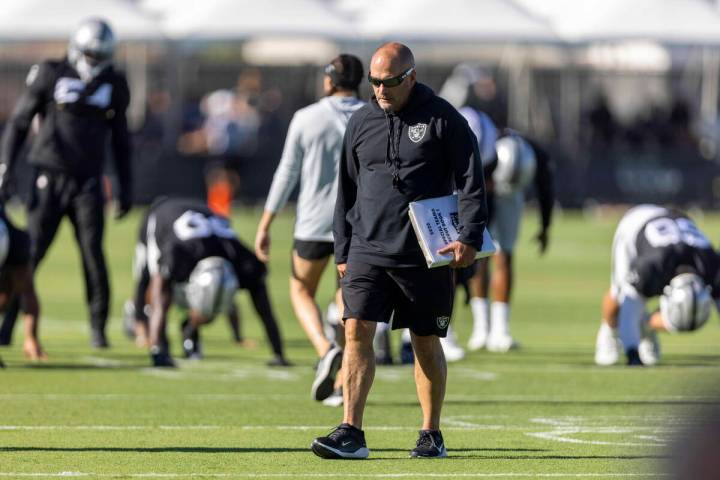 Raiders special teams coordinator Tom McMahon walks the field with his playbook during the team ...