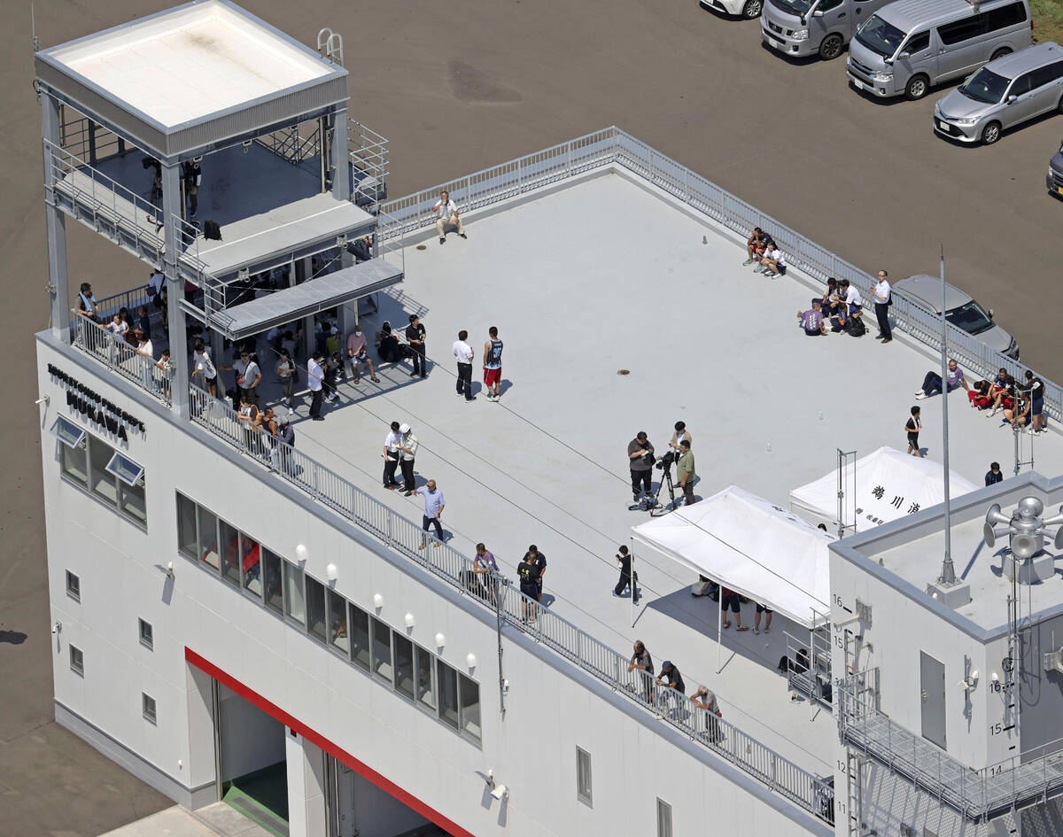People take shelter on the roof of a fire station in Mukawa town, Hokkaido, northern Japan Wedn ...