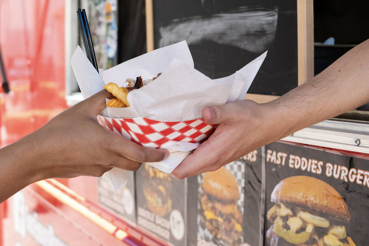 Alex Lasala serves a customer lunch from Fast Eddie’s Burgers food truck parked in front ...