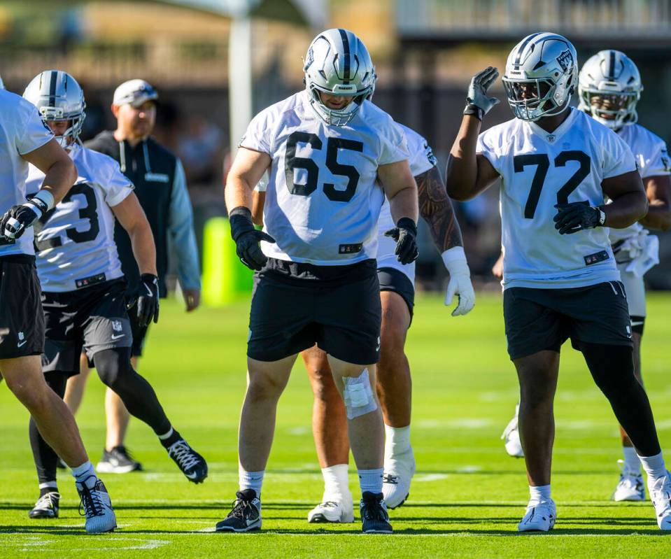Raiders guard Alex Cappa (65) and offensive tackle Gottlieb Ayedze (72) warm up with teammates ...