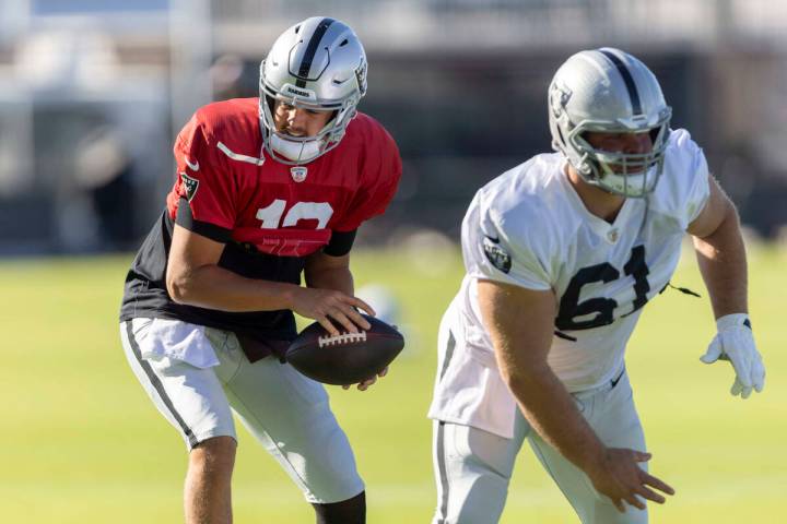 Raiders quarterback Aidan O'Connell (12) takes a snap from guard Jordan Meredith (61) during th ...