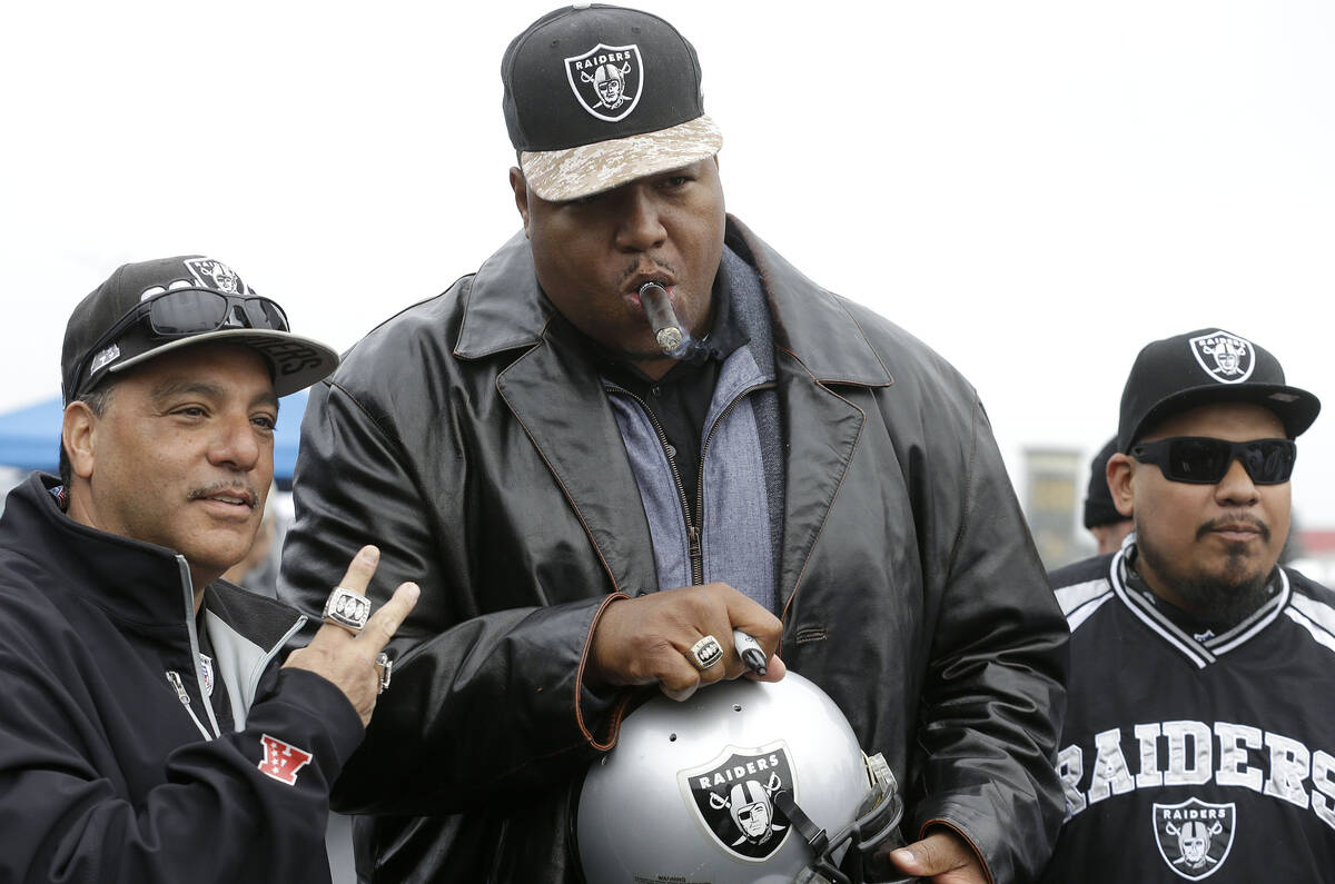 Former Oakland Raiders offensive lineman Lincoln Kennedy, center poses for photos with fans in ...