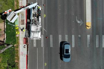 Deon Pace and Jamaine Patton from the City of Las Vegas install a new light and signal pole at ...