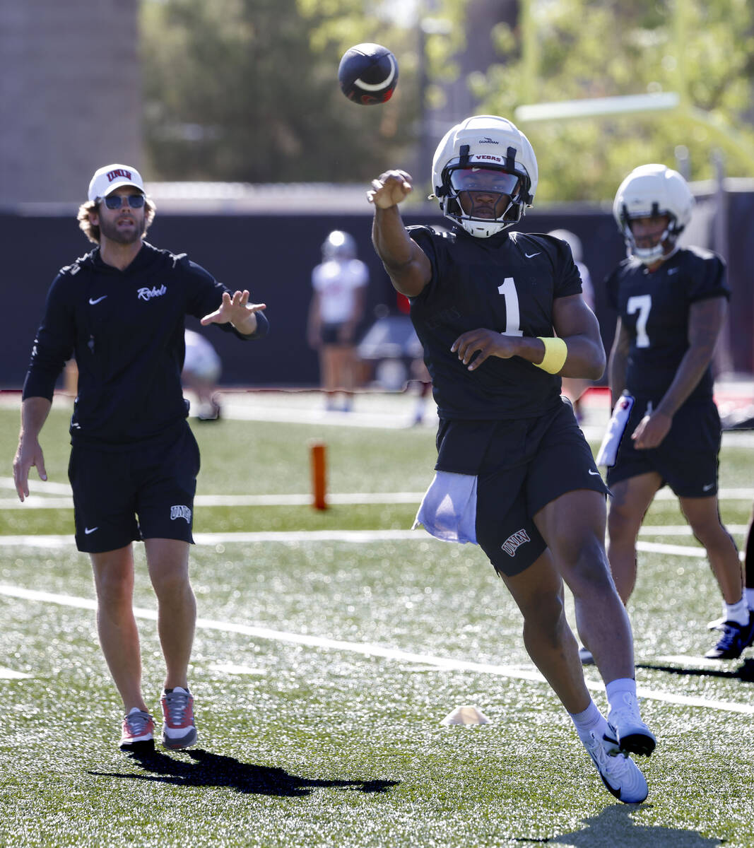 UNLV offensive coordinator Corey Dennis, left, watches as quarterback Alex Orji (1) throw the a ...