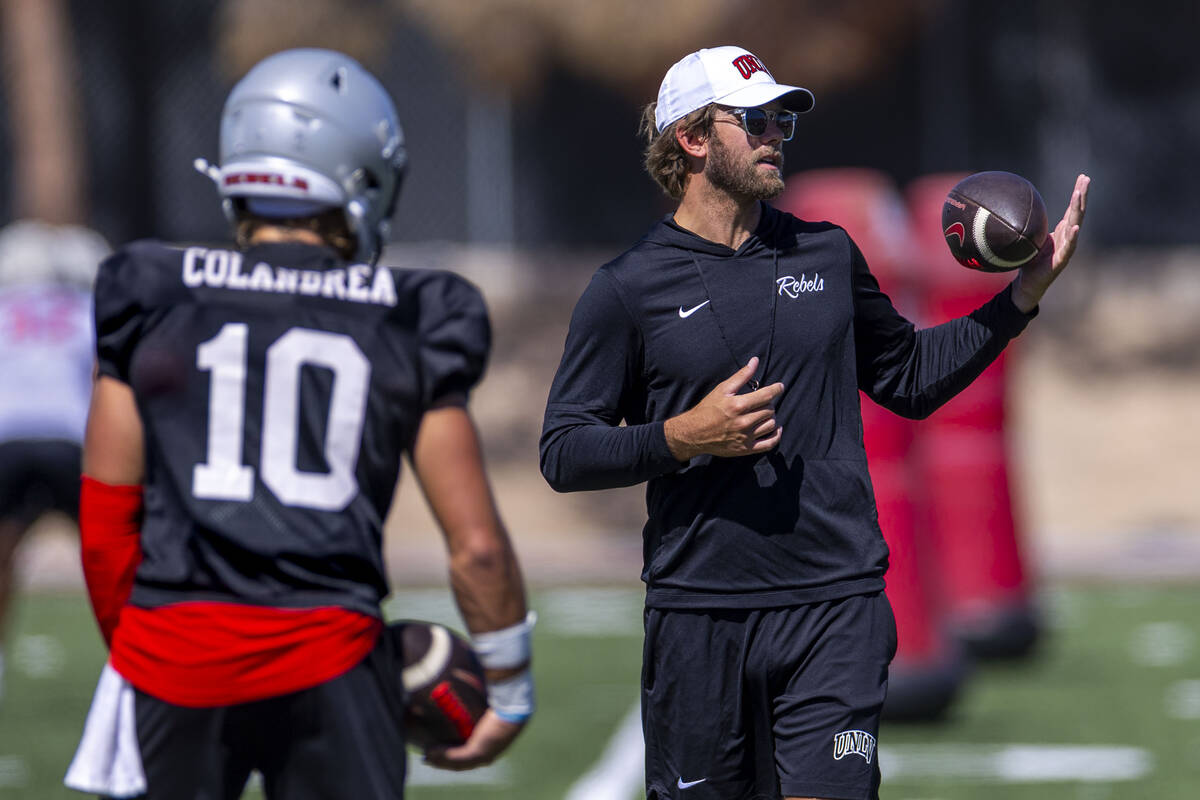 UNLV offensive coordinator and quarterbacks coach Corey Dennis talks technique with quarterback ...