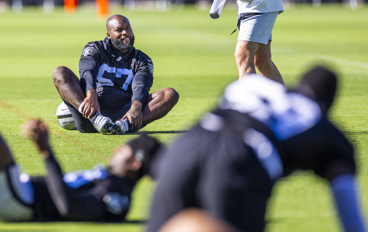 Raiders linebacker Germaine Pratt (57) stretches with teammates as a coach approaches during th ...