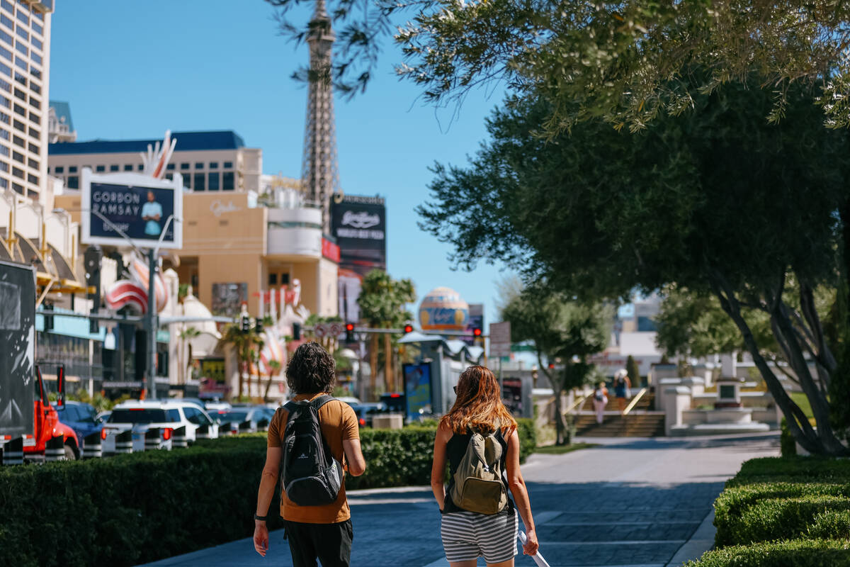 Two pedestrians walk along the sidewalk in front of Caesars Palace on Wednesday, July 30, 2025 ...