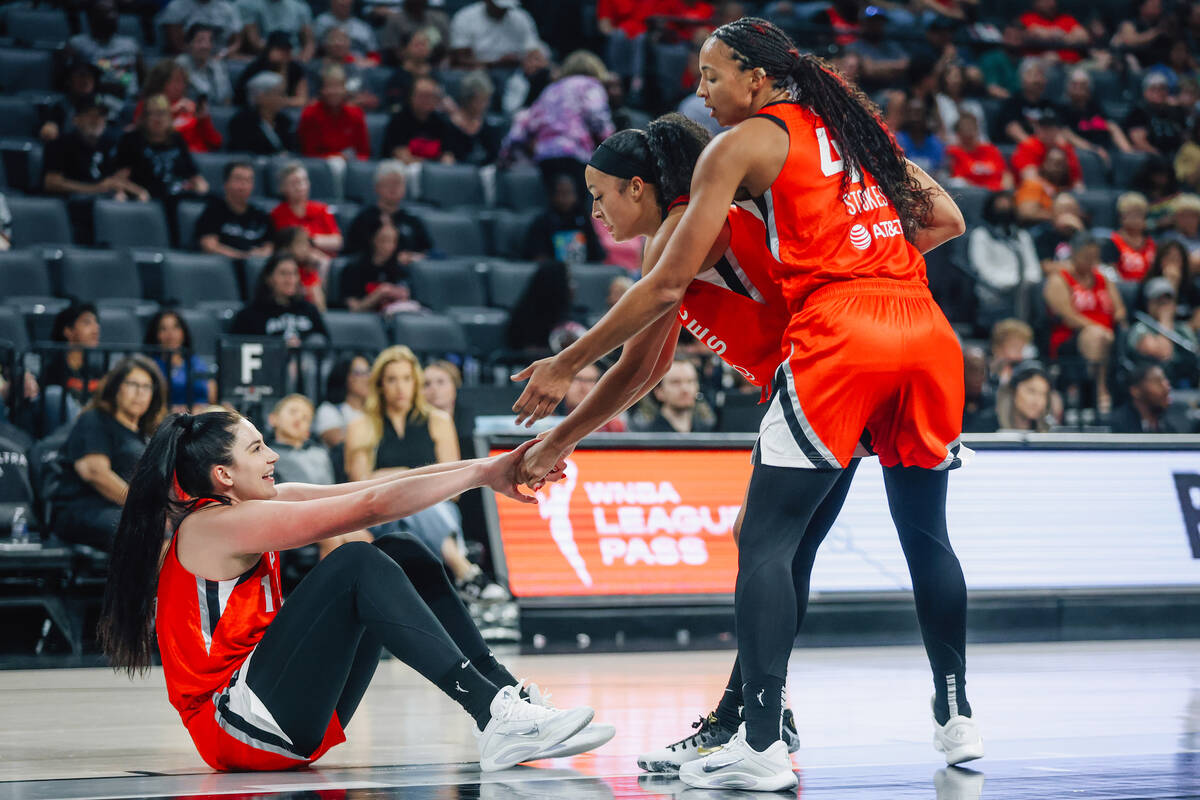 Aces center Megan Gustafson (17) gets help getting up by her teammates during a WNBA basketball ...